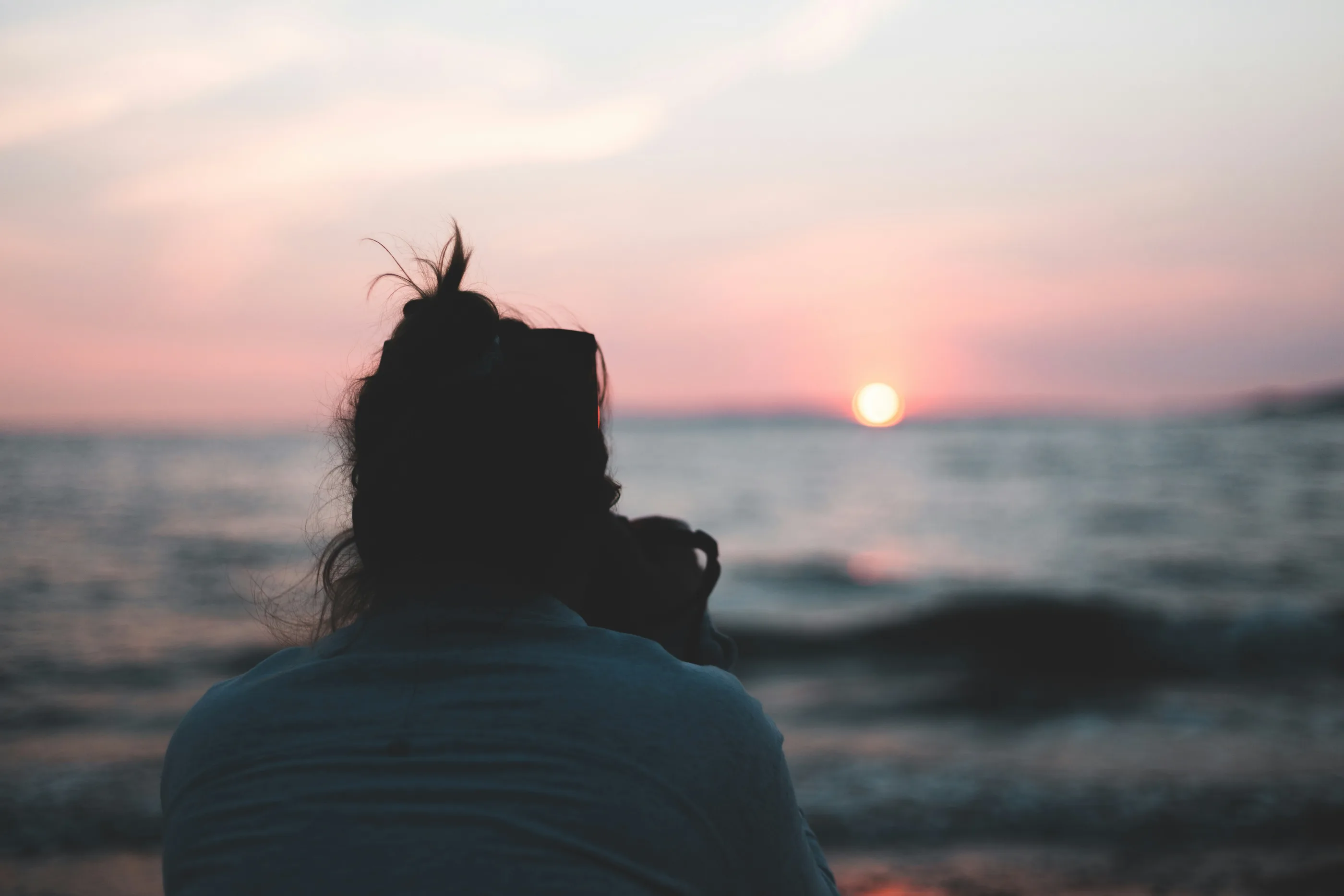 A woman watching the sun set over the sea