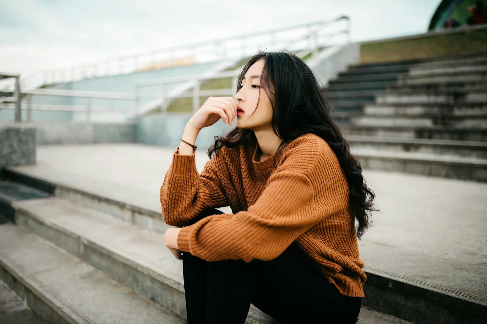 A woman sitting on outdoor steps, thinking