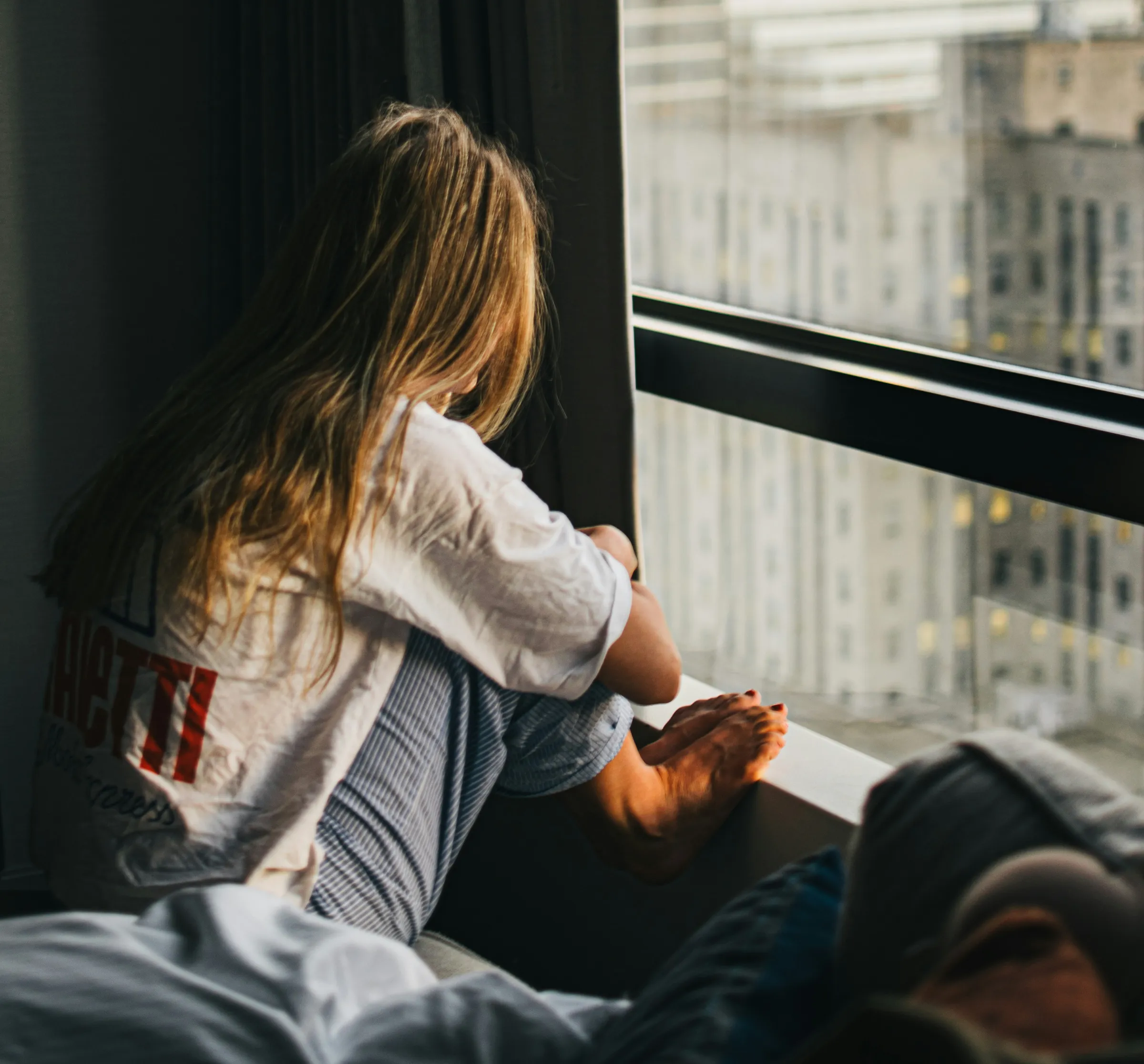 A woman sitting by a window, looking out