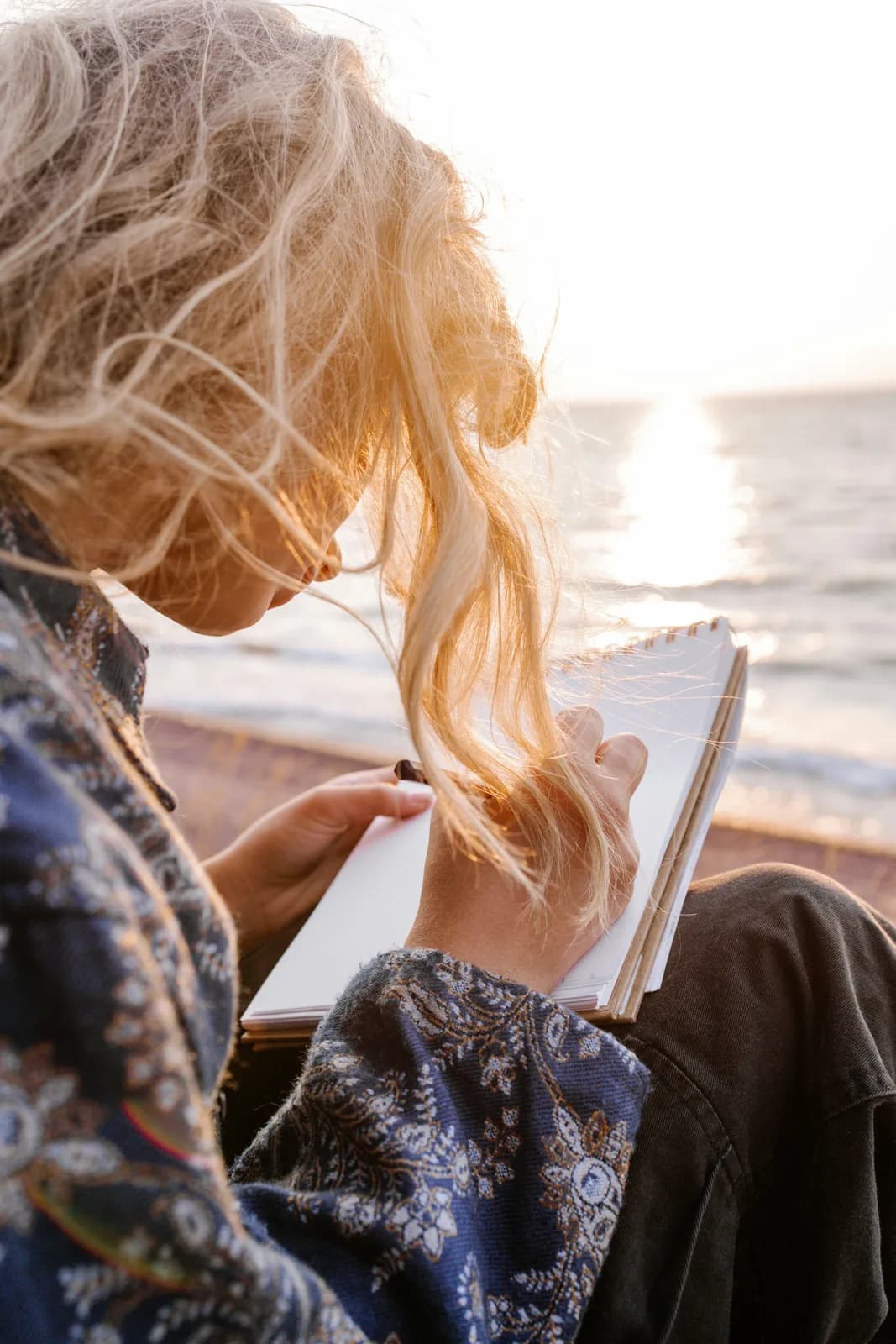A woman writing in a notebook by the sea